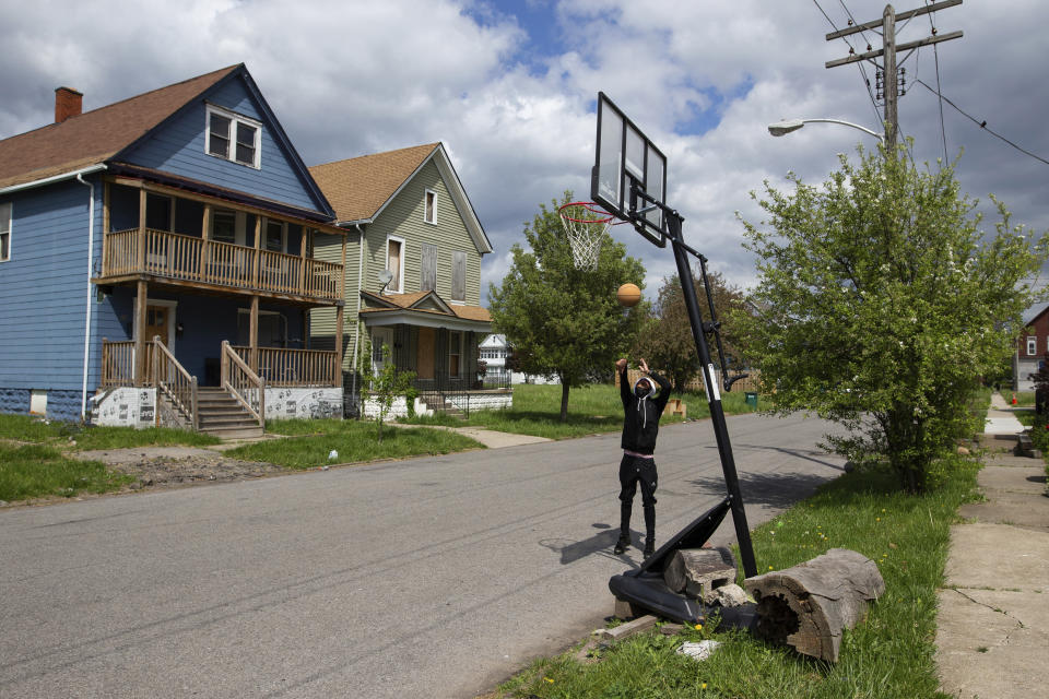 Manny, 17, plays basketball near his house a few blocks from the Tops Friendly Market on Jefferson Avenue on Tuesday, May 17, 2022, in Buffalo, N.Y. As the only supermarket for miles, residents say Tops Friendly Market was a sort of community hub where they chatted with neighbors and caught up on each other’s lives. (AP Photo/Joshua Bessex)