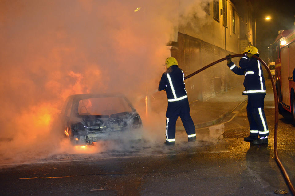 Firefighters extinguish a car fire after rioters attacked Bristol Monday night.