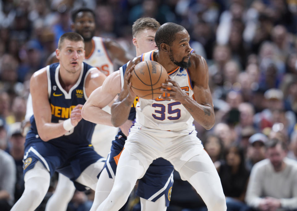 Phoenix Suns forward Kevin Durant, fright, looks to pass the ball as Denver Nuggets guard Christian Braun, center, and center Nikola Jokic, left, defend in the first half of Game 2 of an NBA second-round playoff series Monday, May 1, 2023, in Denver. (AP Photo/David Zalubowski)