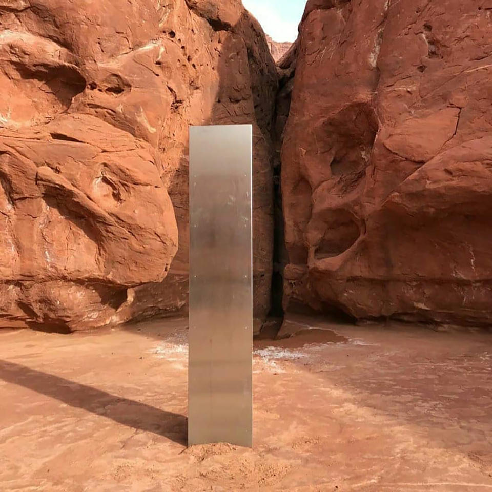 This Nov. 18, 2020 photo provided by the Utah Department of Public Safety shows a metal monolith installed in the ground in a remote area of red rock in Utah. The smooth, tall structure was found during a helicopter survey of bighorn sheep in southeastern Utah, officials said Monday. State workers from the Utah Department of Public Safety and Division of Wildlife Resources spotted the gleaming object from the air and landed nearby to check it out. The exact location is so remote that officials are not revealing it publicly, worried that people might get lost or stranded trying to find it and need to be rescued. (Utah Department of Public Safety via AP)