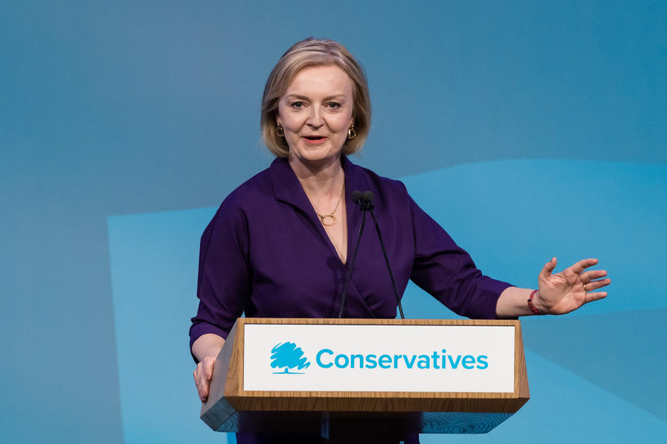 Liz Truss speaks at a podium labeled Conservatives.