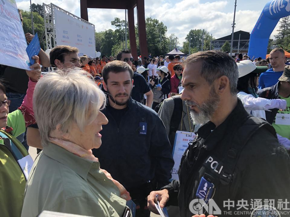世界衛生組織20日舉辦健走活動，台灣宣達團手持「Taiwan」標語遭警方阻止，並盤問協助報名的關懷地球基金會副總裁傅莉（Nicola Spafford Furey, 左）。(中央社)
