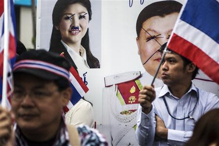 Anti-government protesters stand near the defaced pictures of Thai Prime Minister Yingluck Shinawatra (back L) and Thai Police Major General Wimon Pao-In as they take part in a rally in Bangkok's financial district January 23, 2014. REUTERS/Nir Elias