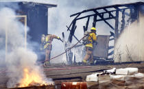 <p>This Friday, Aug. 24, 2018 photo shows firefighters take care of damage at the Hawaiian Dredging base yard in Puamana, Hawaii. Several early morning fires, fed by winds from an approaching Hurricane Lane, destroyed several homes and buildings, including some at the construction company base yard. (Photo: Matthew Thayer/The Maui News via AP) </p>