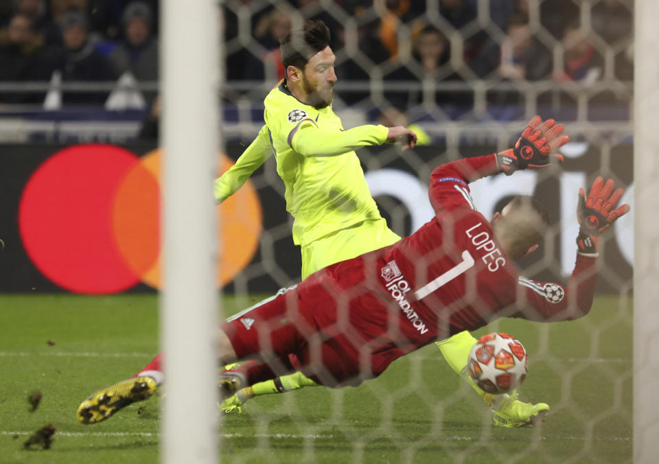 El delantero Lionel Messi del Barcelona remata ante el arquero Anthony Lopes del Lyon en el partido de la fase de octavos de final de la Liga de Campeones en Decines, Francia, el martes 19 de febrero de 2019. (AP Foto/Laurent Cipriani)