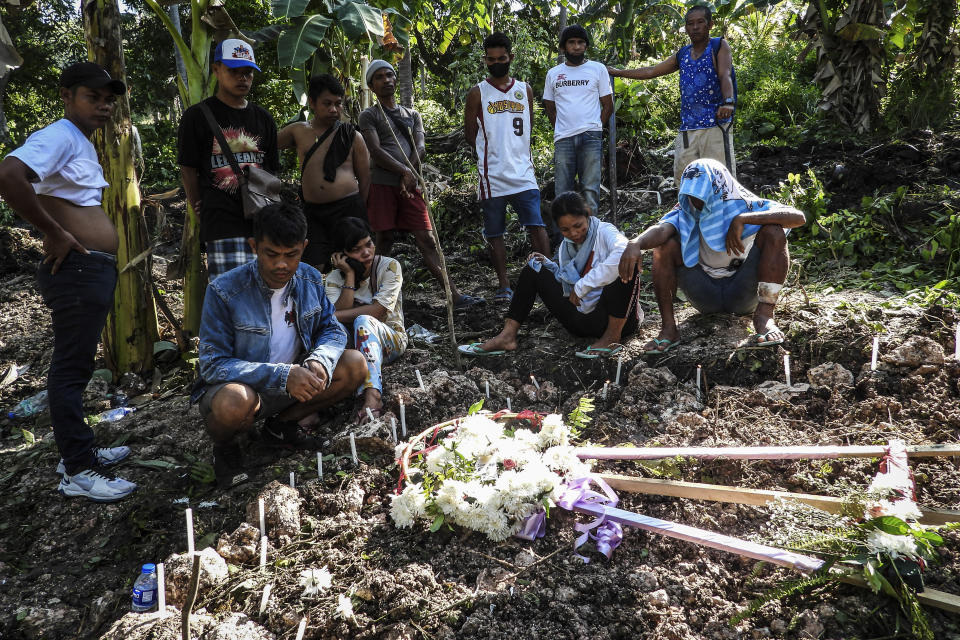 Family members grieve in front of the burial site of their relatives that were retrieved after Tropical Storm Nalgae hit Barangay Kusiong, Datu Odin Sinsuat, Maguindanao province, southern Philippines on Monday Oct. 31, 2022. Philippine officials say more than 100 people have died in one of the most destructive storms to lash the Philippines this year. (AP Photo)