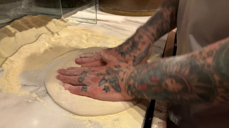 Pressing pizza dough on counter