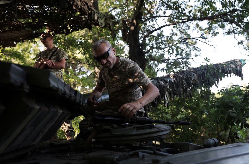 Ukranian servicemen are pictured on a tank hiding with camouflage in a position ready to fire in Kharkiv