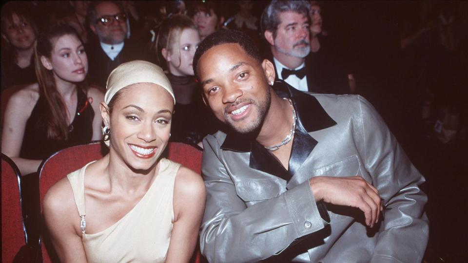 jada pinkett smith and will smith sitting in seats in a theater hall and smiling for the camera