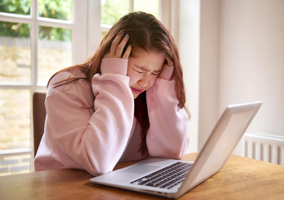 student girl with eyes closed and head in hands crying