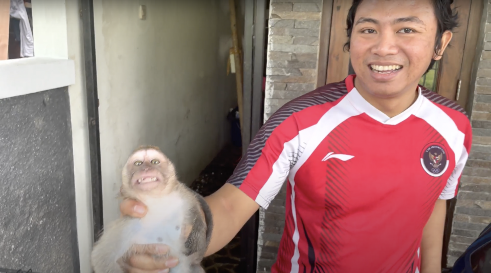 Ajis Rasjana, an Indonesian man who was convicted of animal abuse and sentenced to eight month in prison in the Asian nation, holds a baby monkey known as Mini in an image taken from video shot undercover by the BBC. / Credit: BBC