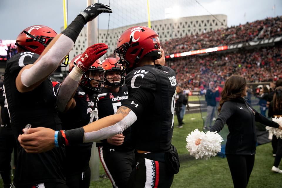 Cincinnati Bearcats quarterback Desmond Ridder (9) celebrates with Cincinnati Bearcats tight end Josh Whyle (81) and Cincinnati Bearcats running back Ryan Montgomery (22) after scoring a touchdown in the first half of the NCAA football game between the Cincinnati Bearcats and the Southern Methodist Mustangs on Saturday, Nov. 20, 2021, at Nippert Stadium in Cincinnati. 