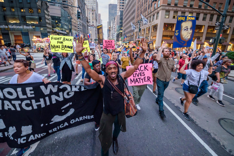 Protesters marching in the streets. Some hold up signs reading: Black lives matter.