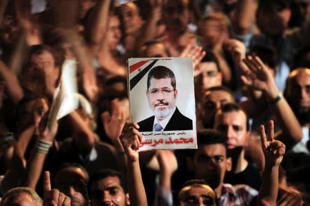 A picture of Egypt's first Islamist President Mohamed Mursi is held up as supporters cheer during a rally at Tahrir Square in Cairo