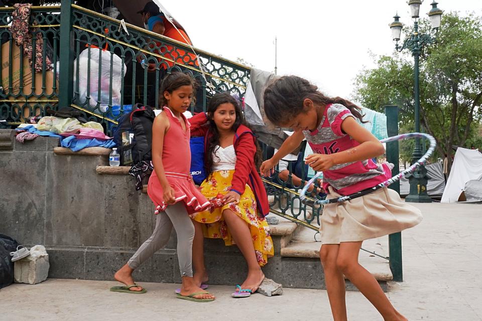 Girls play or sit on steps nearby