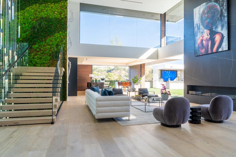 An indoor lounge area with a couch, staircase, several chairs and a long fireplace.