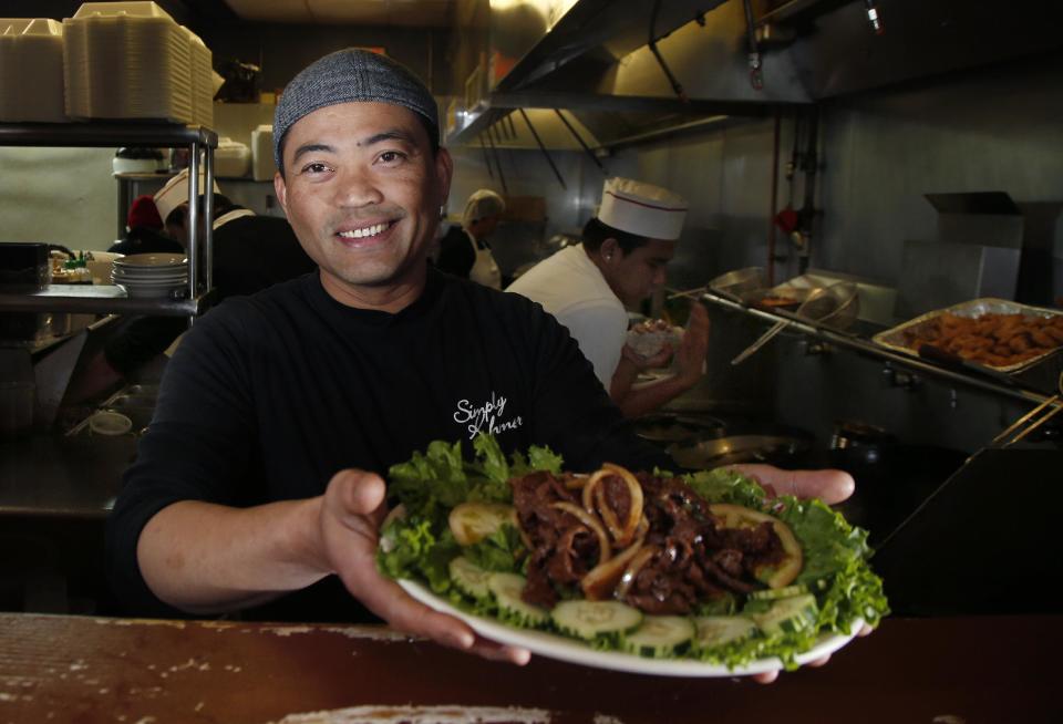 This March 14, 2014 photo shows chef Sambath Neang of Cambodian restaurant Simply Khmer presenting a beef loc lac plate during lunchtime in Lowell, Mass. The classic Cambodian dish consists of seared beef that has been marinated and cooked in a savory sauce made with garlic, soy sauce, sugar and other ingredients. Simply Khmer is considered by some to offer the best _ and most authentic _ Cambodian food in Lowell. (AP Photo/Elise Amendola)