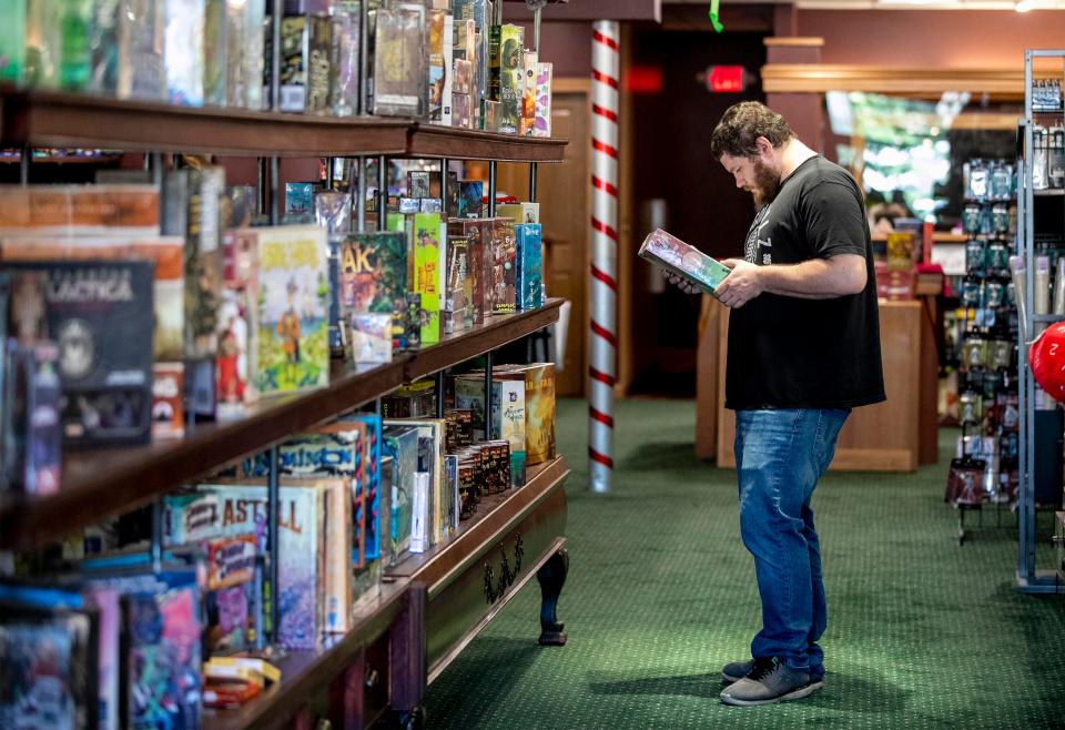 Erik Olson, Brandon, Wis. looks over games at The GameBoard,Thursday, July 14, 2022, in Sheboygan, Wis. Olson, who has an interest in board games, was in Sheboygan to check out the store.