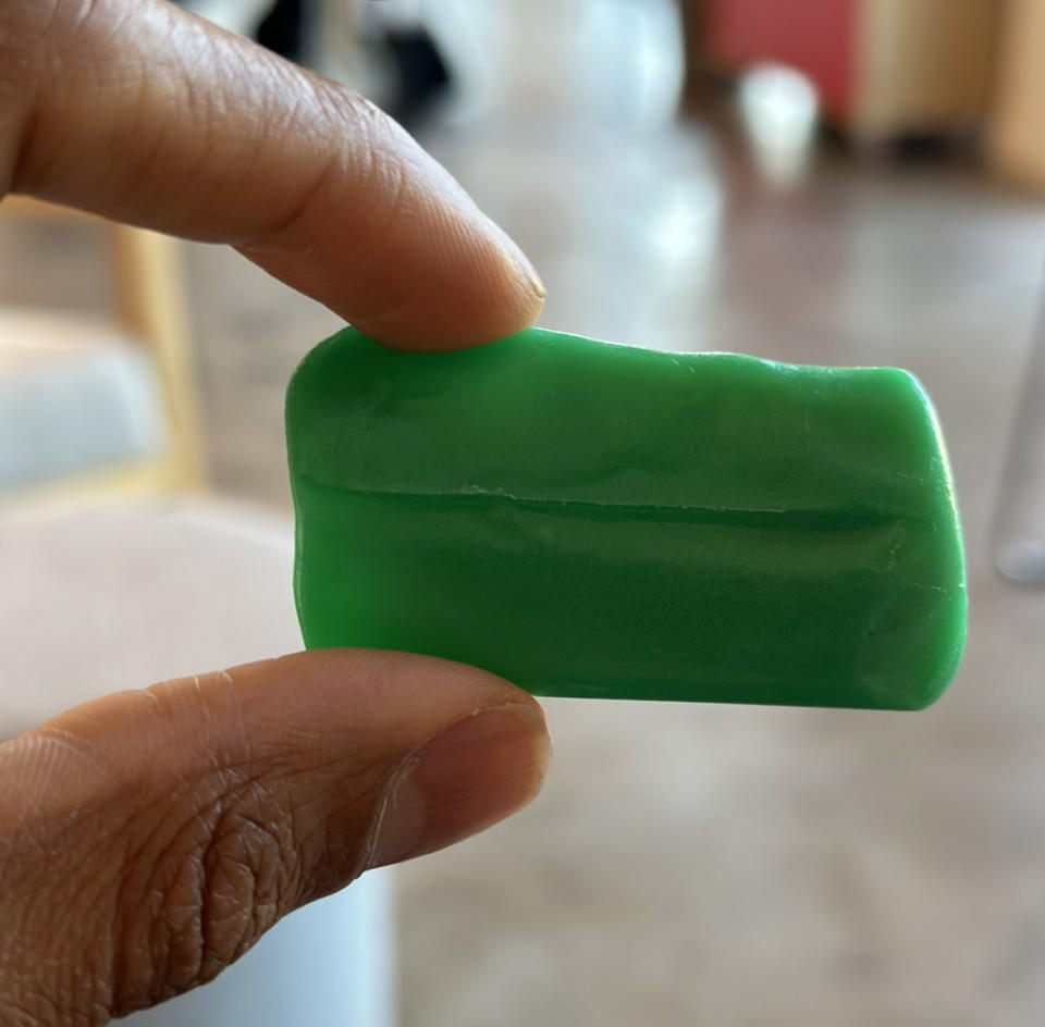 A hand holding a greenish, rectangular candy