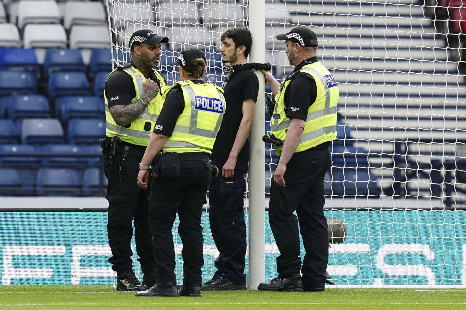 Police speak to a protestor wearing a "Red Card For Israel" T-Shirt after he chained himself to a goalpost ahead of the UEFA Women's Euro 2025 qualifying match between Scotland and Israel, at Hampden Park in Glasgow, Scotland, Friday May 31, 2024. (Jane Barlow/PA via AP)