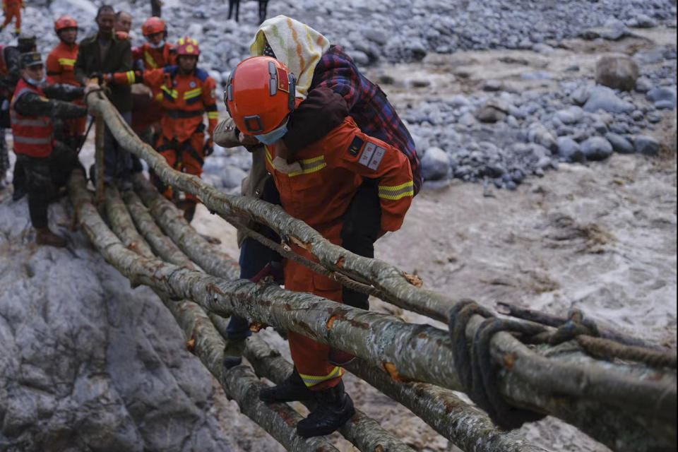 In this photo released by Xinhua News Agency, rescuers carry a villager across a river following an earthquake in Moxi Town of Luding County, southwest China's Sichuan Province on Monday, Sept. 5, 2022. Dozens people were reported killed and missing in a 6.8 magnitude earthquake that shook China's southwestern province of Sichuan on Monday, triggering landslides and shaking buildings in the provincial capital of Chengdu, whose 21 million residents are already under a COVID-19 lockdown. (Cheng Xueli/Xinhua via AP)