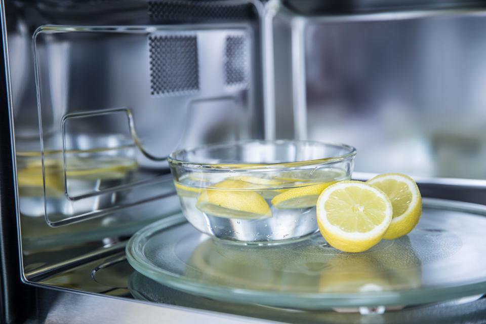 Slices of lemon in bowl of water in microwave
