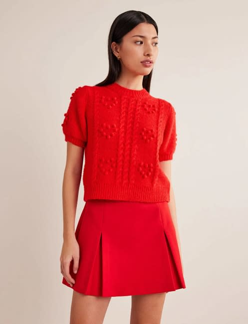 a model wearing the same red knitted top as holly