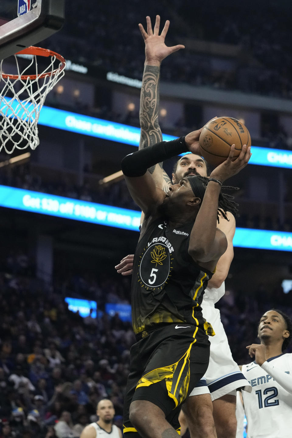 Golden State Warriors forward Kevon Looney (5) shoots against Memphis Grizzlies center Steven Adams, background, during the first half of an NBA basketball game in San Francisco, Sunday, Dec. 25, 2022. (AP Photo/Godofredo A. Vásquez)