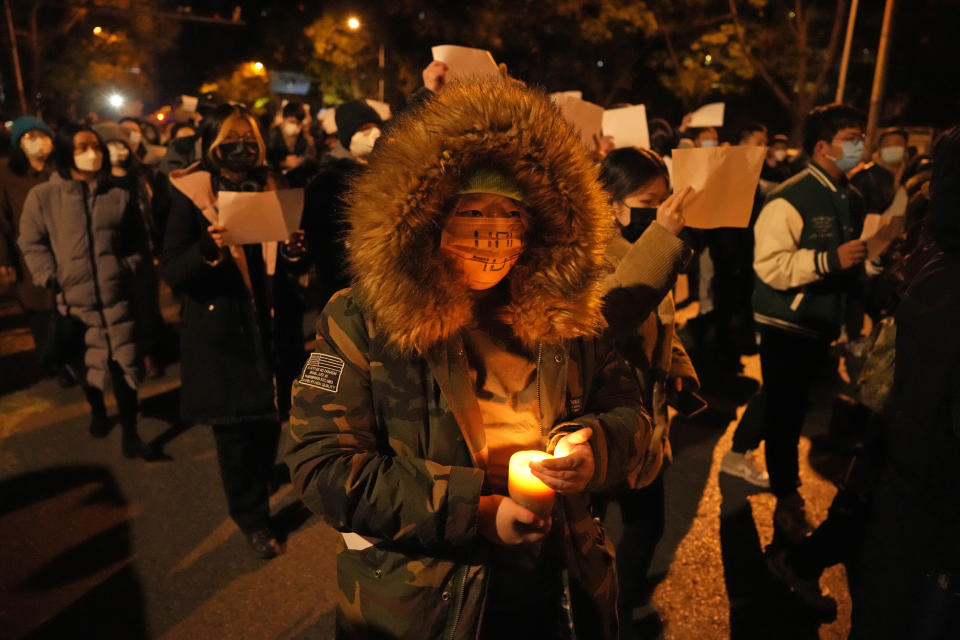 Protesters hold up blank papers and chant slogans as they march in protest against strict anti-virus measures in Beijing, Sunday, Nov. 27, 2022. (AP Photo/Ng Han Guan)