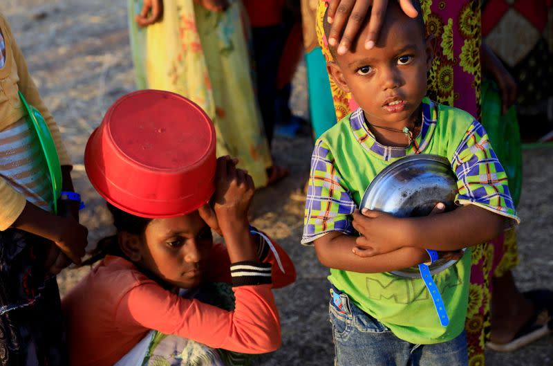 An Ethiopian child who fled war in Tigray region, carries his plate as he queues for wet food ration at the Um-Rakoba camp, on the Sudan-Ethiopia border in Al-Qadarif state