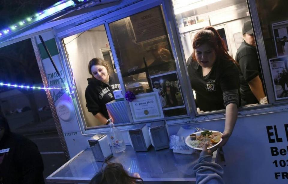 Alejandra Gonzalez, left, and Bianca Loza, right, of El Premio Mayor serve free tacos to the homeless outside Poverello House in this Fresno Bee file photo from 2017.