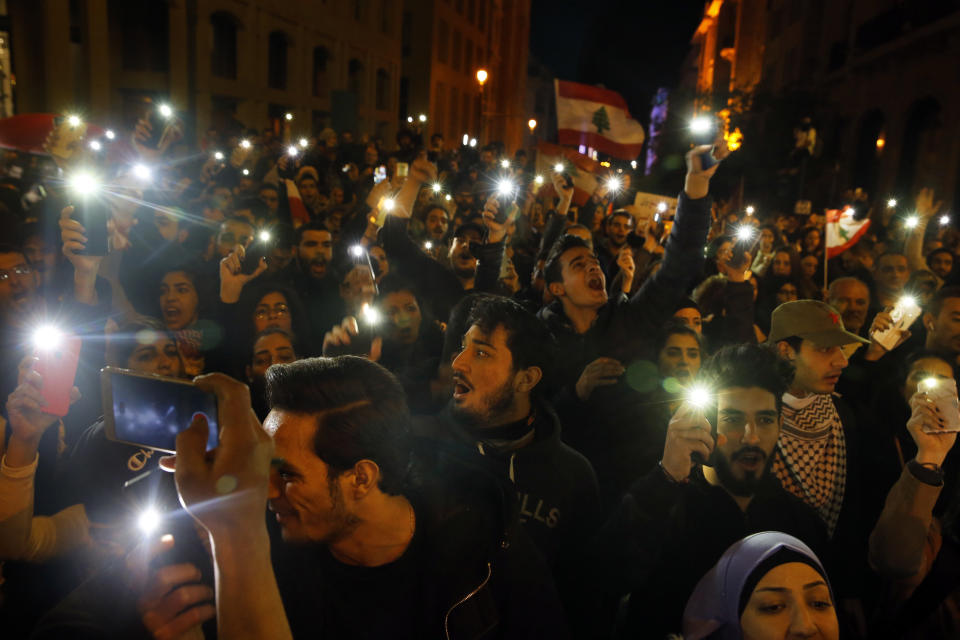 Anti-government demonstrators chant slogans as they light up their mobile phones during a protest at a road leading to the parliament building in Beirut, Lebanon, Thursday, Jan. 16, 2020. Lebanese protesters Thursday decried security forces' use of violence during rallies over the past two days, including attacks on journalists and the detention of over 100 people. (AP Photo/Bilal Hussein)