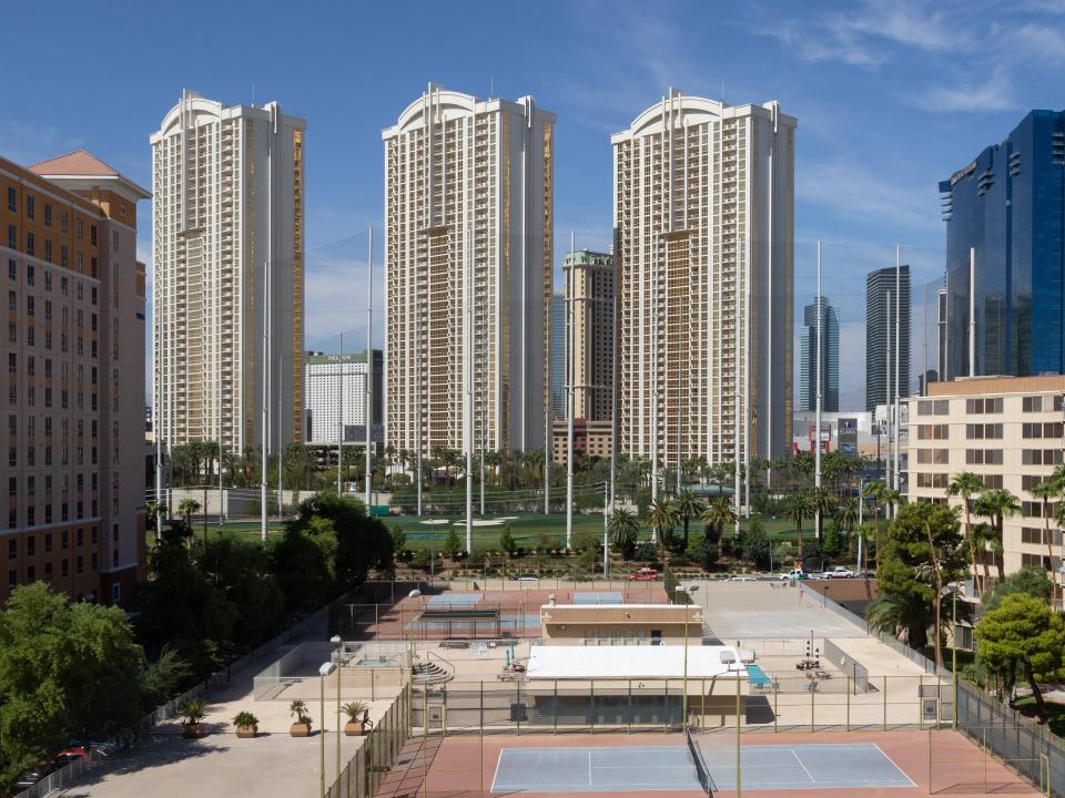 Tall buildings with a tennis court in the foreground.
