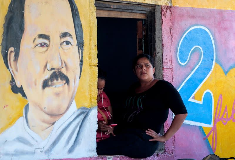 FILE PHOTO: A woman sits next to an image of Nicaragua's President Daniel Ortega in Catarina