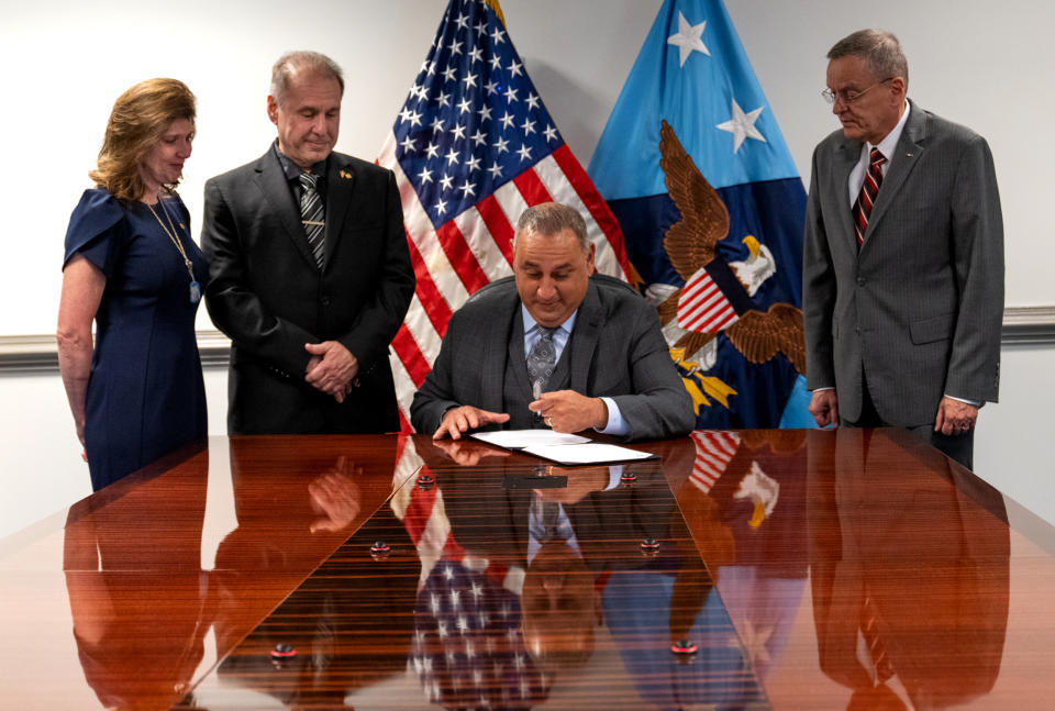 Image: Undersecretary of Defense for Personnel and Readiness Gilbert Cisneros signs a policy to implement the Brandon Act at the Pentagon in Washington on Friday. Teri and Patrick Caserta, left, joined the signing ceremony. (Tech. Sgt. Jack Sanders / Department of Defense)