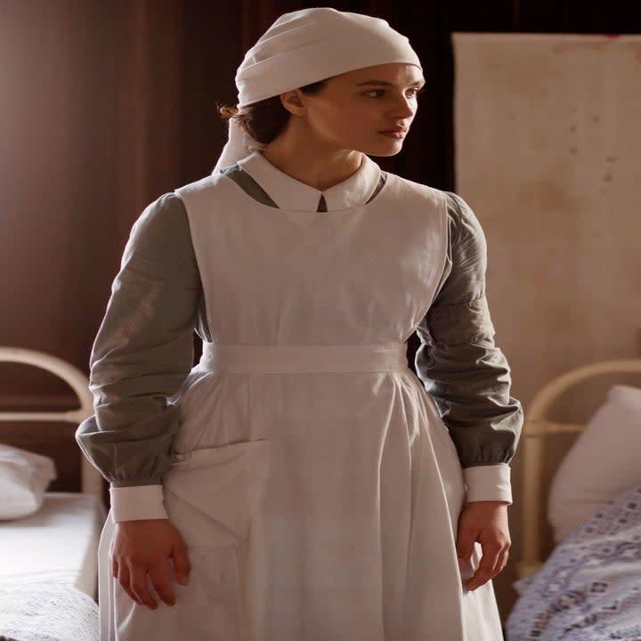 Lady Sybil stands in a hospital. She wears a nurses uniform.