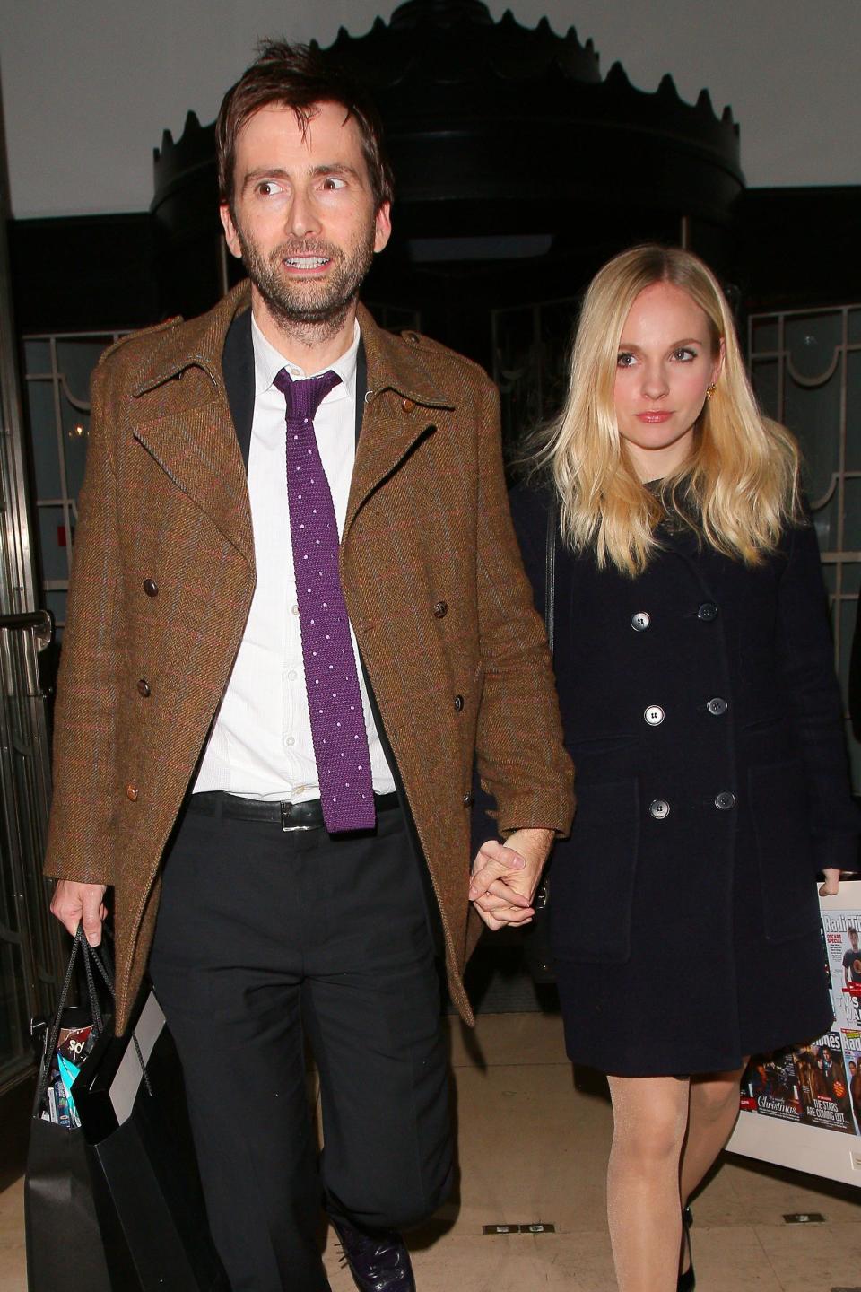 David Tennant and Georgia Tennant holding hands, walking with shopping bags, and dressed in smart casual attire