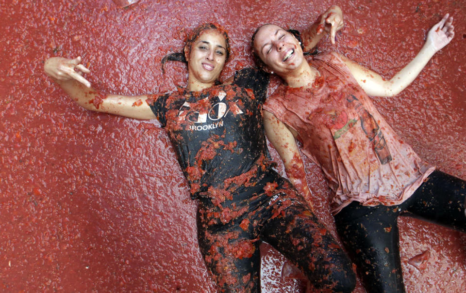 <p>Two girls pose as they lie in a puddle of squashed tomatoes, during the annual “Tomatina”, tomato fight fiesta, in the village of Bunol, 50 kilometers outside Valencia, Spain, Aug. 31, 2016. (Photo: Alberto Saiz/AP)</p>