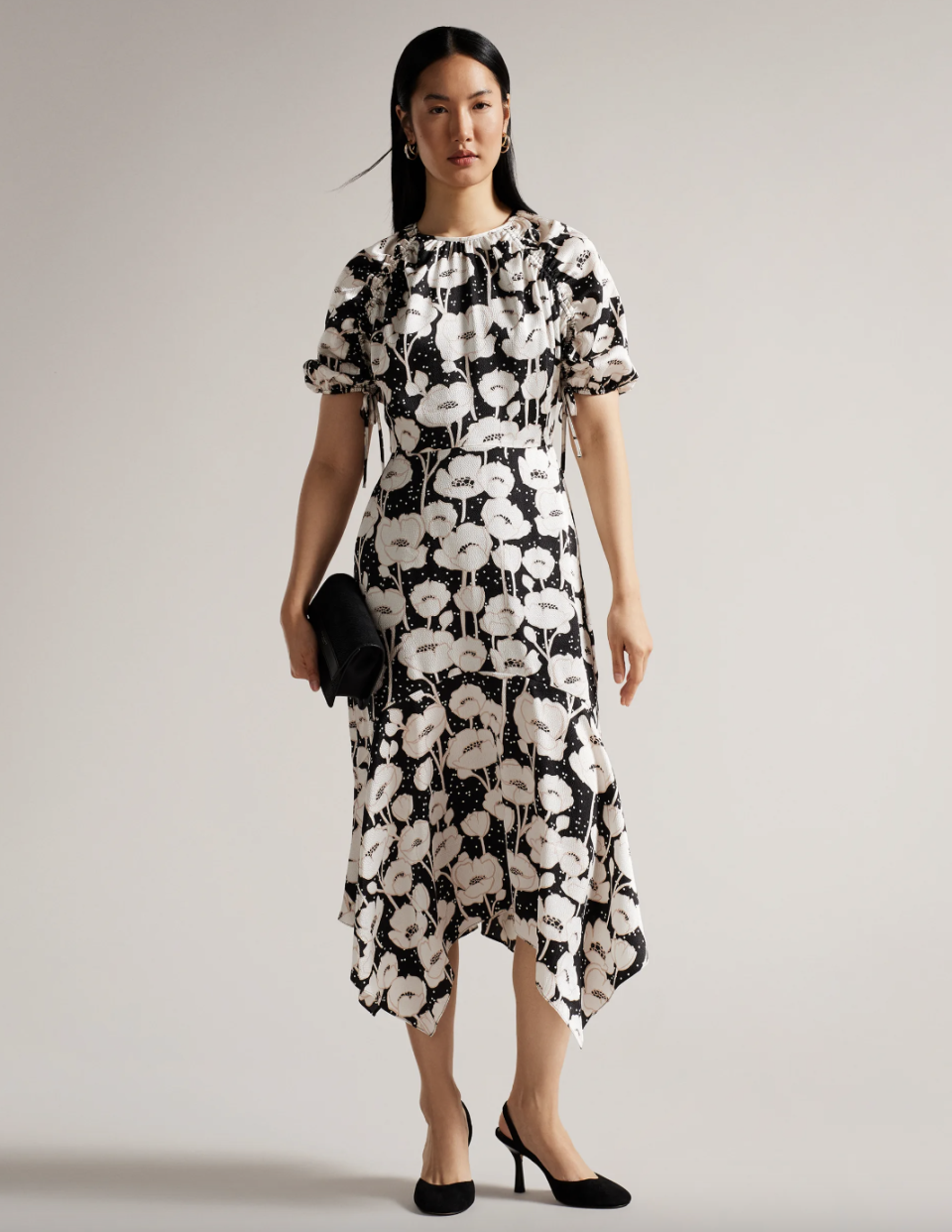 asian model with black hair wearing black heels and white and black floral print Abriee Puff Sleeve Midi Dress (photo via Ted Baker)