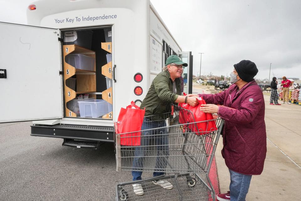 Driver Bill Raymond helps Corene Scott load her groceries into the Senior Access van outside of an H-E-B on Feb. 7. The nonprofit has been providing free transportation to older adults for 30 years.