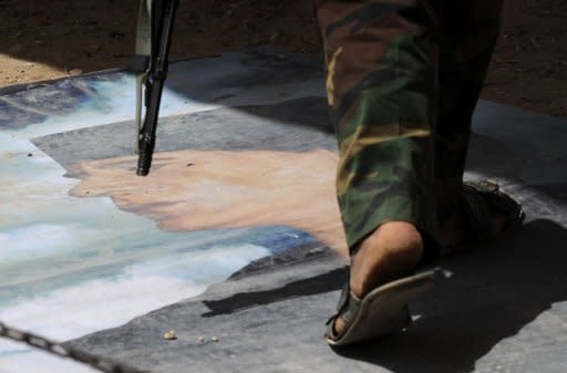 An NTC fighter walks over an image of Libyan strongman Moamer Kadhafi at an outpost in Tarhuna, southeast of Tripoli. Fighters for Libya's new rulers on Saturday began an assault to overrun a bastion of Moamer Kadhafi, as secret files shed light on his fallen regime's links to US and British spy agencies