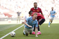 Manchester City's Kevin De Bruyne, foreground, grimaces in pain after a tackle by Manchester United's Fred, center, during the English FA Cup final soccer match between Manchester City and Manchester United at Wembley Stadium in London, Saturday, June 3, 2023. (AP Photo/Dave Thompson)