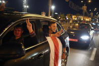 Two protesters with an old Belarusian national flag gesture form their car during an opposition rally to protest the presidential inauguration in Minsk, Belarus, Wednesday, Sept. 23, 2020. Belarus President Alexander Lukashenko has been sworn in to his sixth term in office at an inaugural ceremony that was not announced in advance amid weeks of huge protests saying the authoritarian leader's reelection was rigged. Hundreds took to the streets in several cities in the evening to protest the inauguration. (AP Photo/TUT.by)