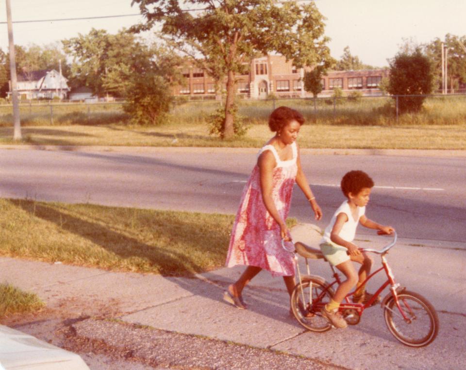 Jessie Richardson, left, with grandson Tyrone Gridiron (3), in front of their home on St. Joseph and Everett. The photo was taken after the demolishing in 1965-1966 of more than 600 homes in the area. Photo was taken just prior to the beginning of construction. Across the median the Main Street School can be seen.