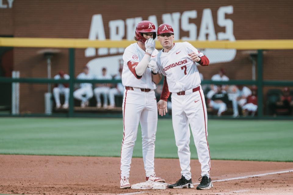 Arkansas baseball's Ben McLaughlin (left) and assistant coach Bobby Wernes have a discussion during the Razorbacks' 2-1 win over Florida Friday, April 26, 2024.