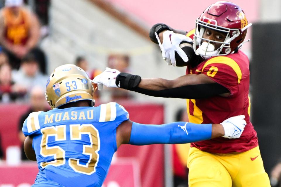 USC running back MarShawn Lloyd, right, tries to avoid UCLA linebacker Darius Muasau during the first half.