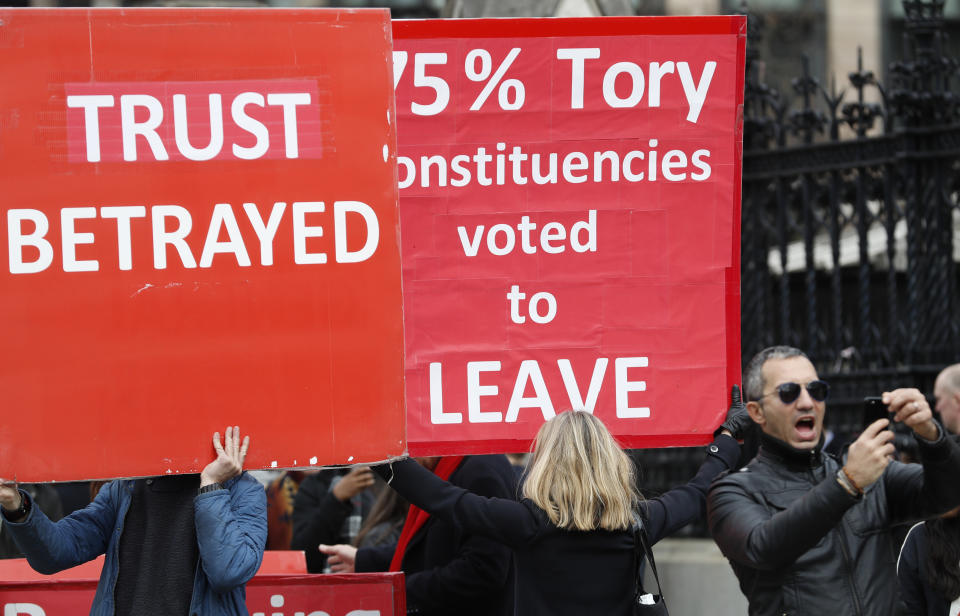 A tourist takes a photo on a smart phone as Pro-Brexit protesters holds onto placards as they demonstrates near the House of Parliament in London, Tuesday, March 26, 2019. British Prime Minister Theresa May's government says Parliament's decision to take control of the stalled process of leaving the European Union underscores the need for lawmakers to approve her twice-defeated deal. (AP Photo/Alastair Grant)