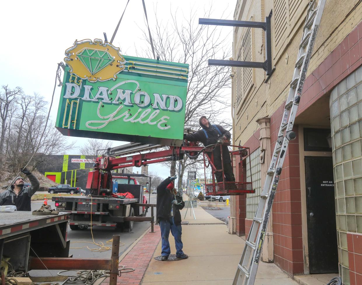 Workers from Adams Signs hoist the refurbished iconic sign of the Diamond Grille on Friday as they prepare to secure it in place.