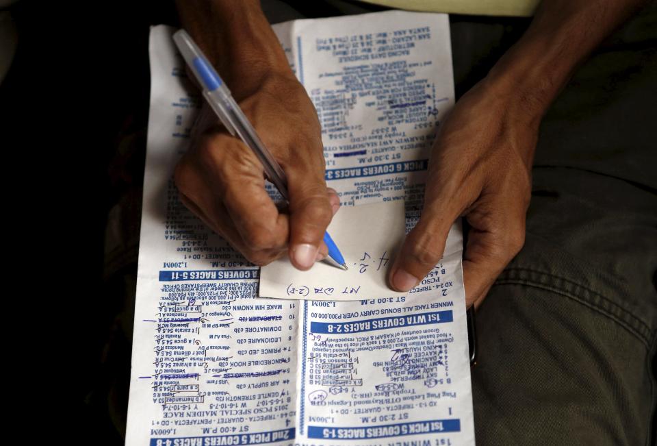 A gambler writes his horse racing bet on a piece of paper in Malabon, Metro Manila, Philippines March 21, 2015. Horseracing yields one of the more popular forms of sports betting, both legal and illegal, in the Philippines. When paying your final respects for a relative or friend, the last thing you might expect to see at the wake is people placing bets on a card game or bingo. Not in the Philippines. Filipinos, like many Asians, love their gambling. But making wagers on games such as "sakla", the local version of Spanish tarot cards, is particularly common at wakes because the family of the deceased gets a share of the winnings to help cover funeral expenses. Authorities have sought to regulate betting but illegal games persist, with men and women, rich and poor, betting on anything from cockfighting to the Basque hard-rubber ball game of jai-alai, basketball to spider races. Many told Reuters photographer Erik De Castro that gambling is only an entertaining diversion in a country where two-fifths of the population live on $2 a day. But he found that some gamble every day. Casino security personnel told of customers begging to be banned from the premises, while a financier who lends gamblers money at high interest described the dozens of vehicles and wads of land titles given as collateral by those hoping lady luck would bring them riches. REUTERS/Erik De Castro PICTURE 23 OF 29 FOR WIDER IMAGE STORY "HIGH STAKES IN MANILA". SEARCH "BINGO ERIK" FOR ALL IMAGES.