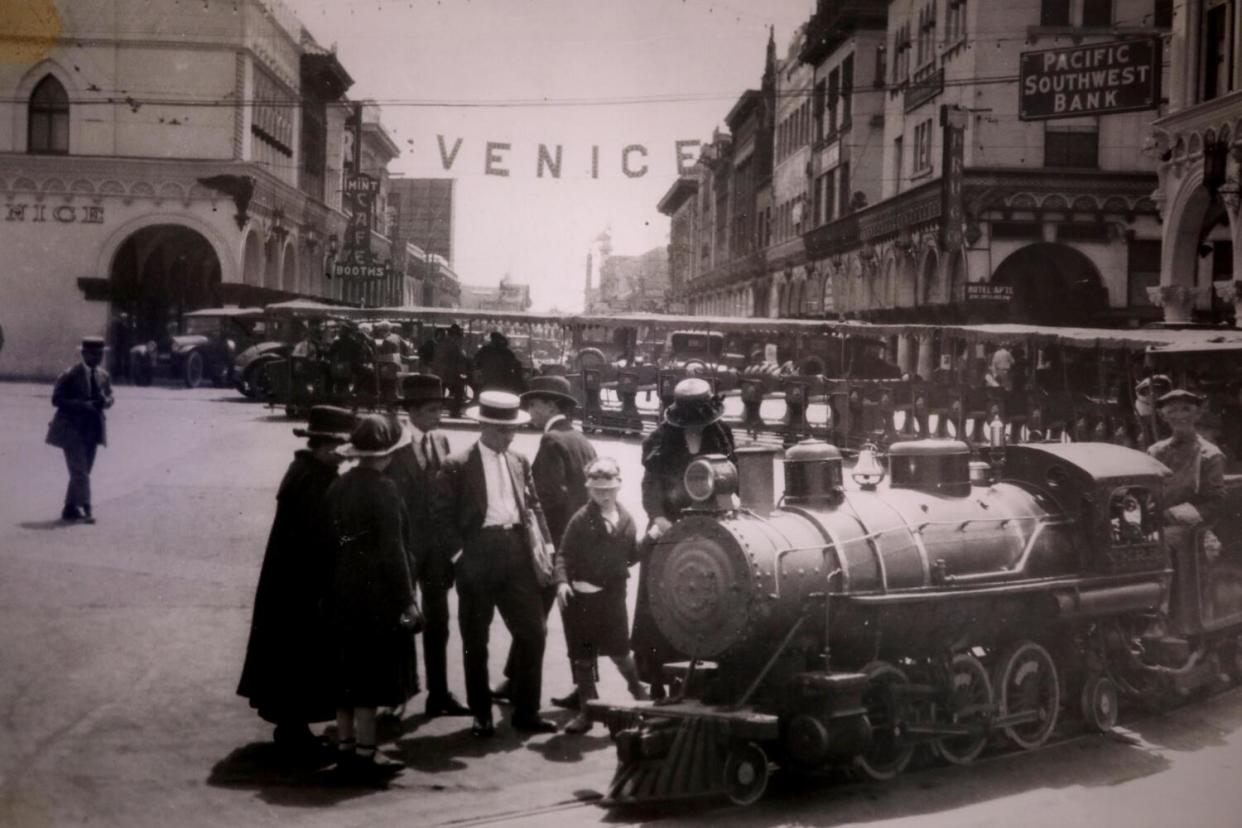 An old photo shows people in period dress with a train.